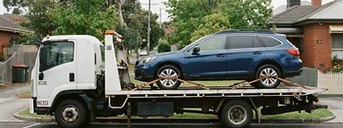 A disabled vehicle being loaded onto a tilt-tray tow truck at the roadside