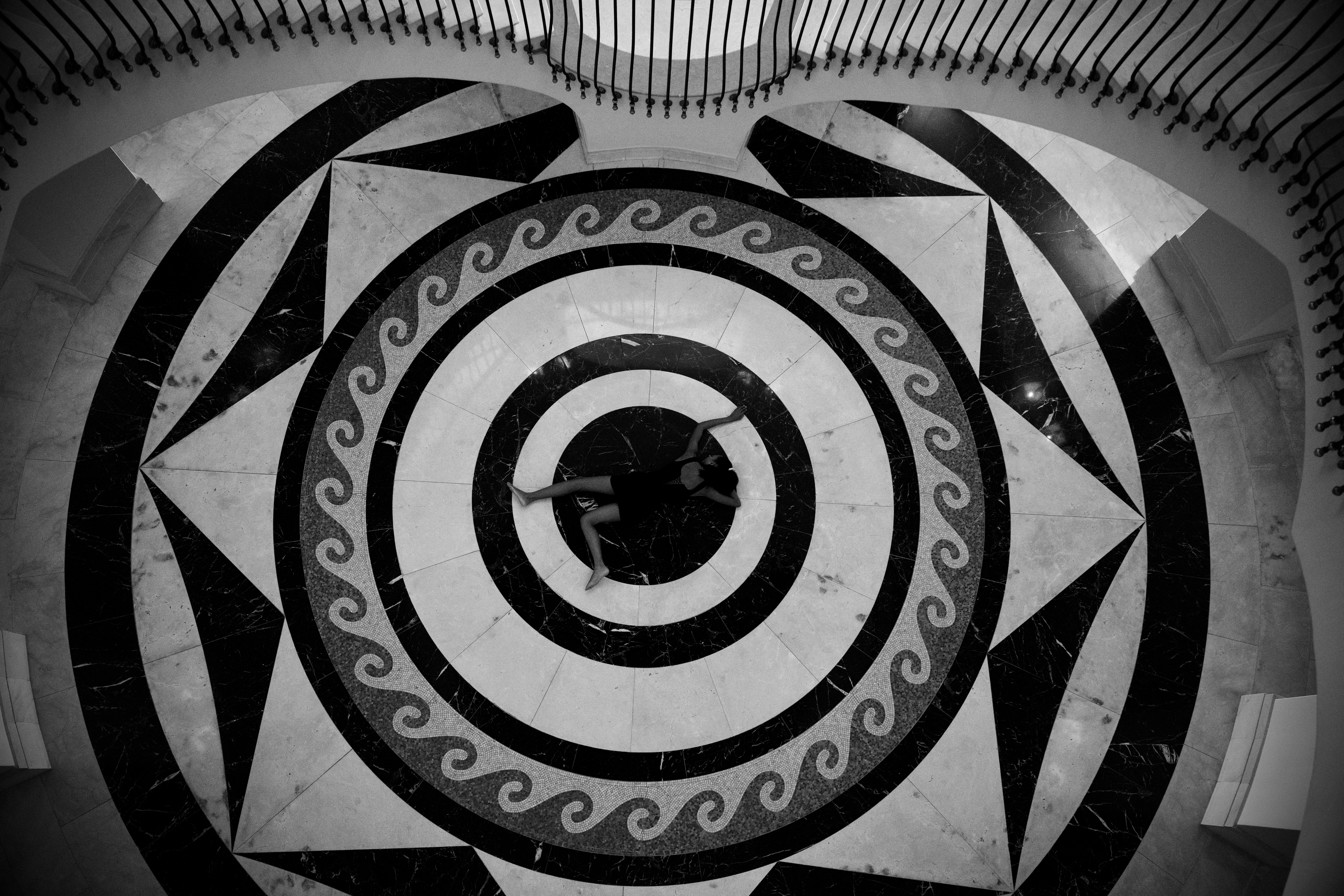 Black and white self-portrait lying at the centre of a mosaic floor