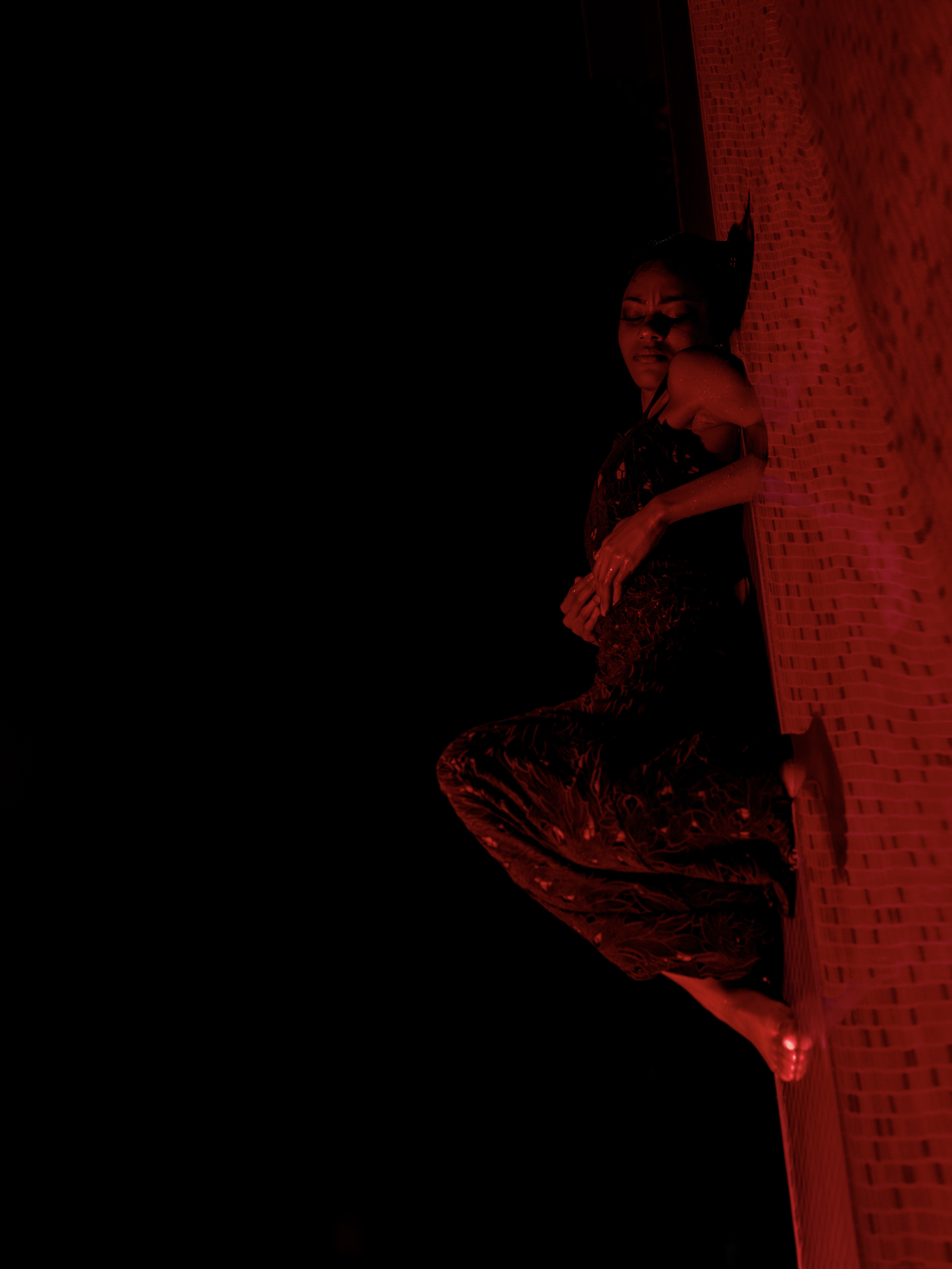 Self-portrait in red light against a brick wall
