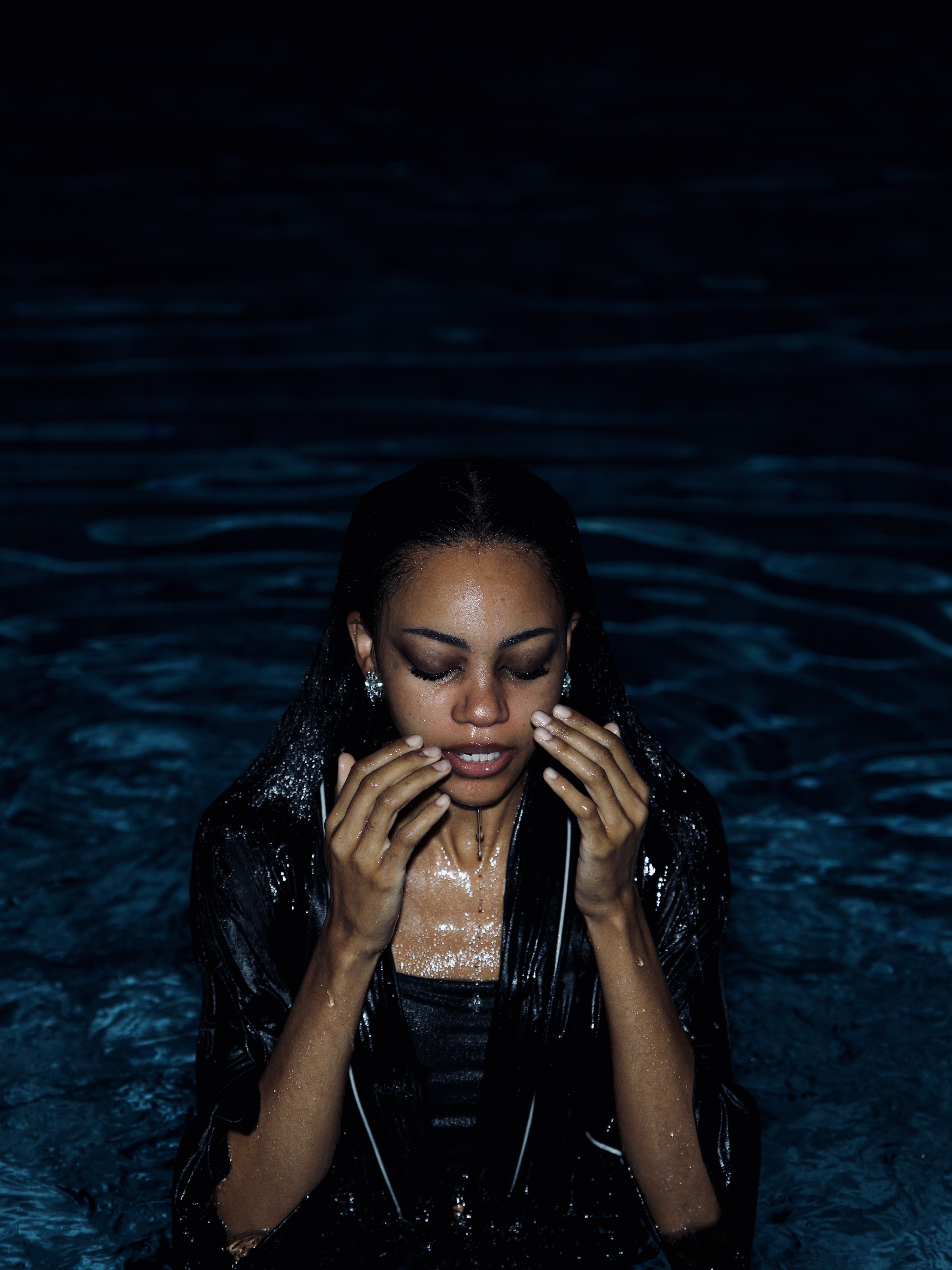 Self-portrait in dark water with hands at the face