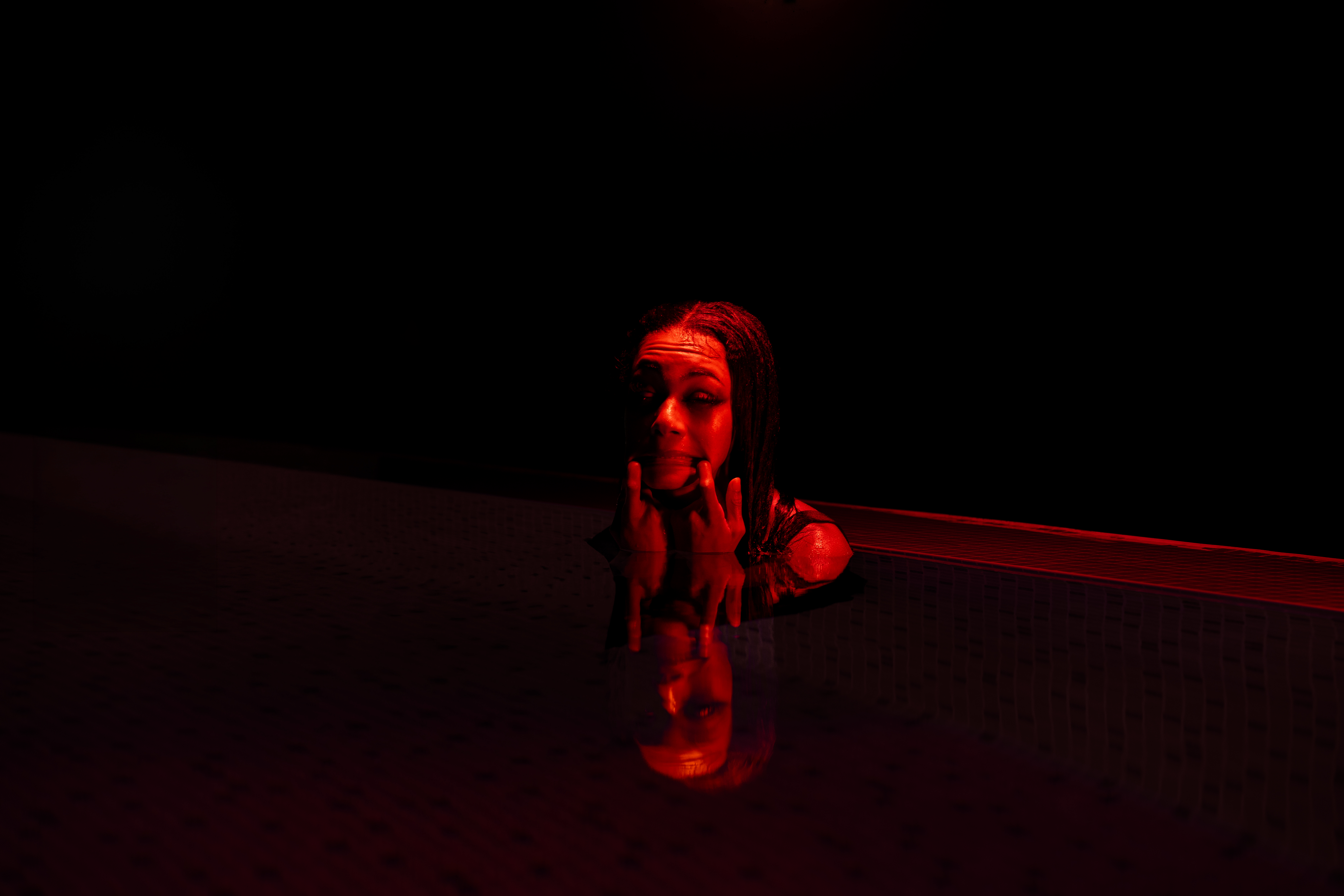Self-portrait in a pool under red light with reflection