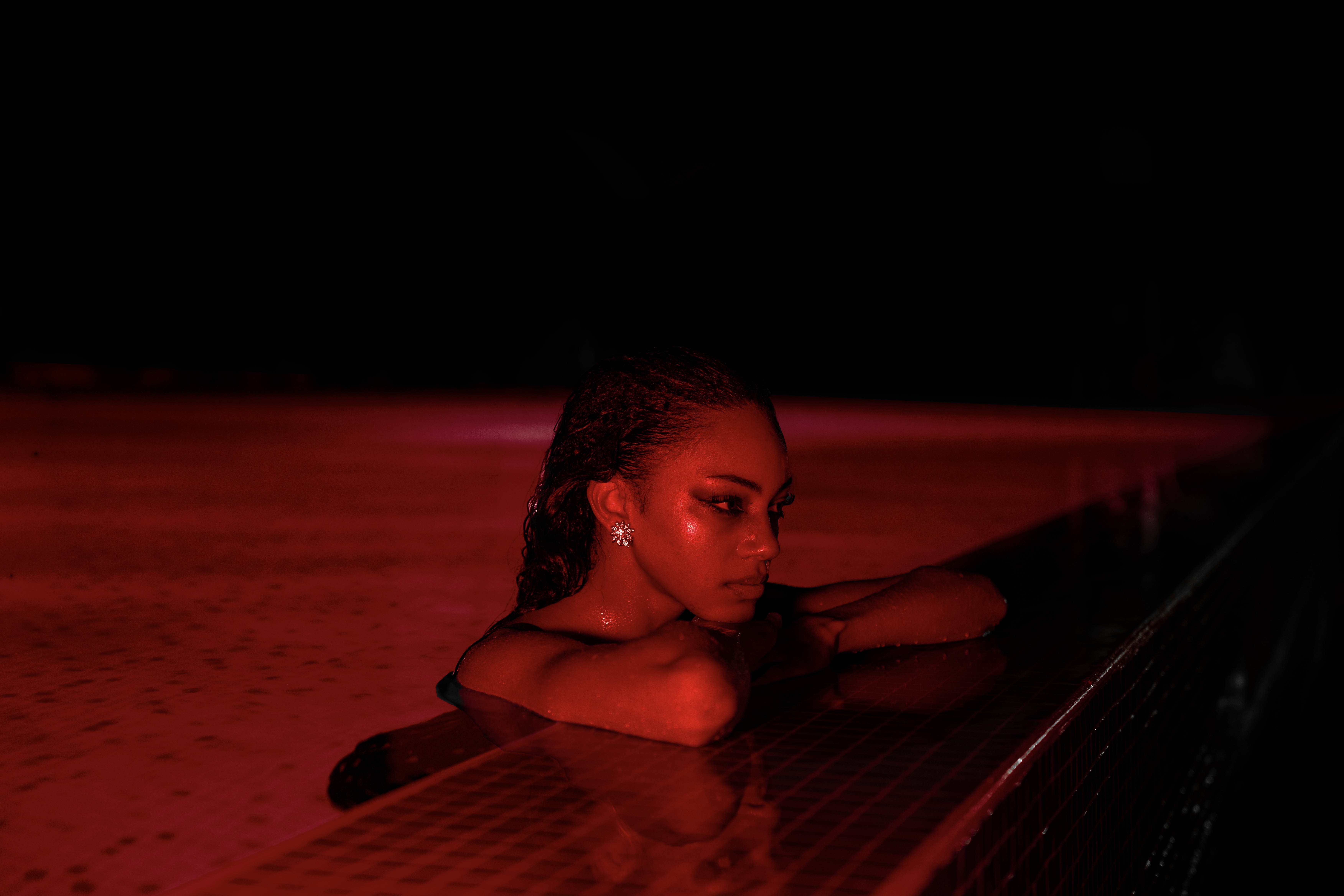 Self-portrait resting on the pool edge in red light