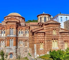Exterior view of the Byzantine Hosios Loukas Monastery with its domes and bell tower under a blue sky