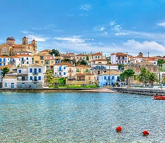 Harbour view of Galaxidi with traditional houses, domed church, and red fishing boats on a sunny day