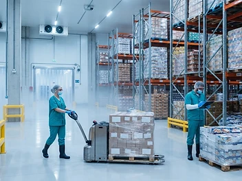 Camp-Tisha cold-chain warehouse with organized frozen food pallet racks and staff in teal uniforms and PPE