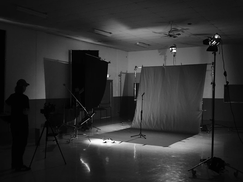 Moody black-and-white photography studio — camera, backdrop and lit sneakers