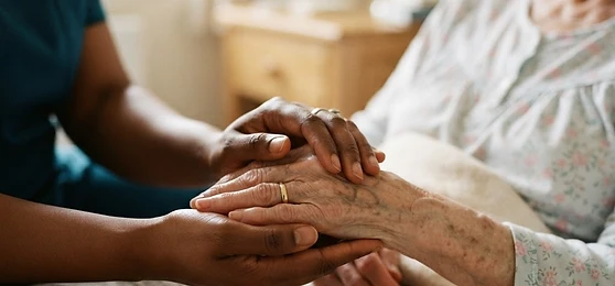 A caregiver gently holding an elderly person's hand