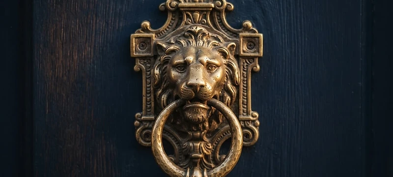 Macro detail of a burnished brass door knocker on a deep navy door