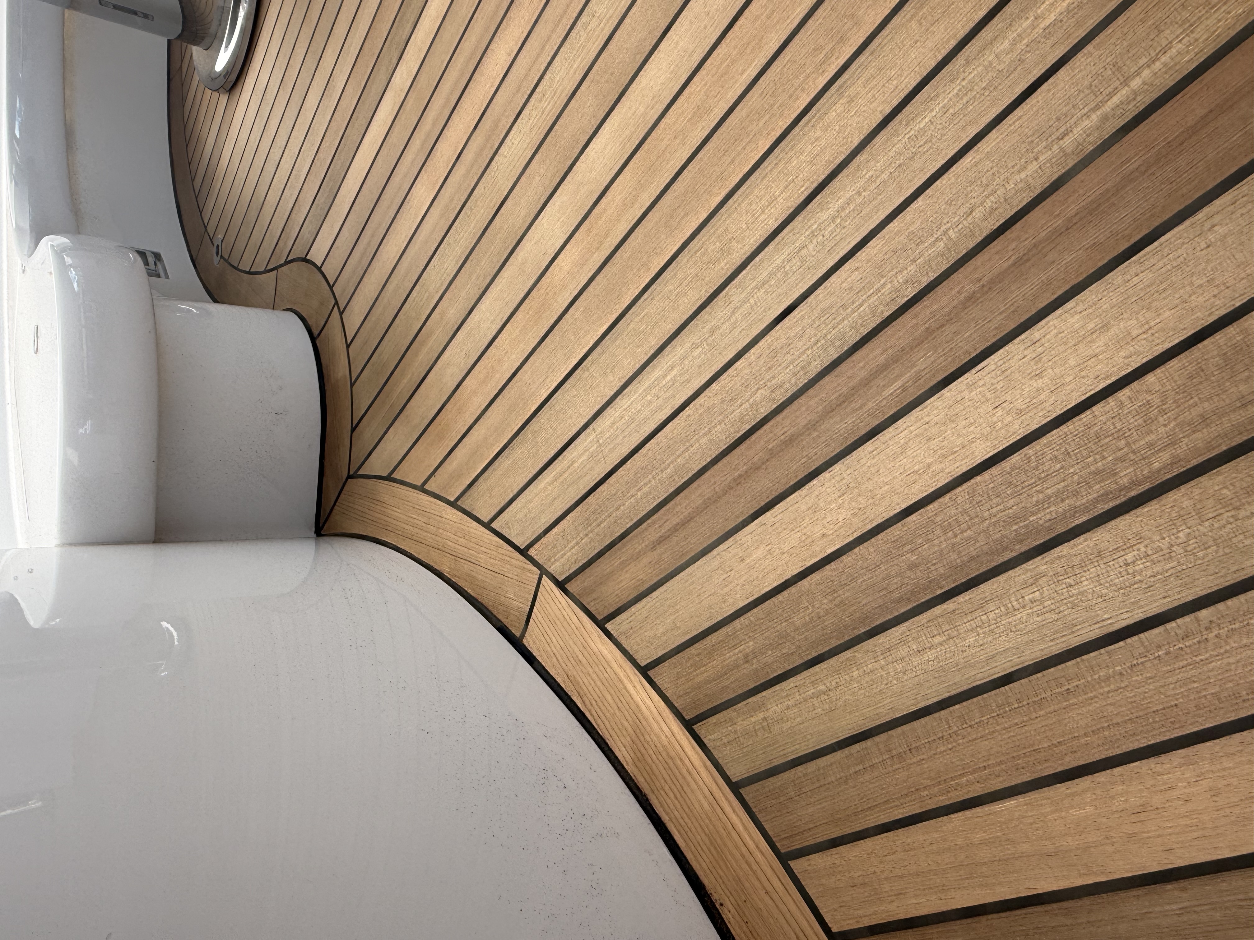Curved teak deck with clean black caulking lines on a yacht prepared by Teak Techs