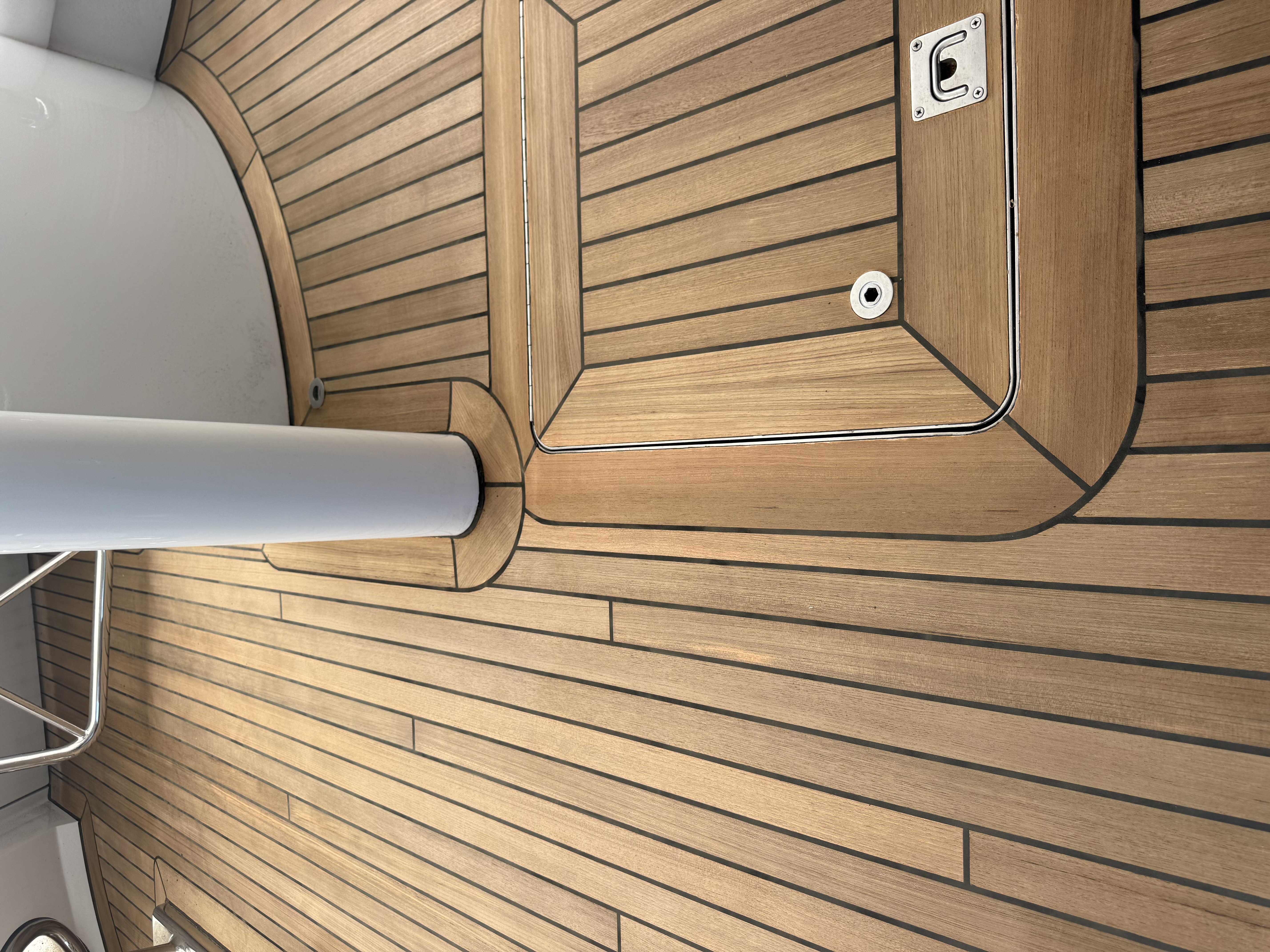Teak deck with a flush-mounted hatch and stainless hardware, finished by Teak Techs marine carpenters