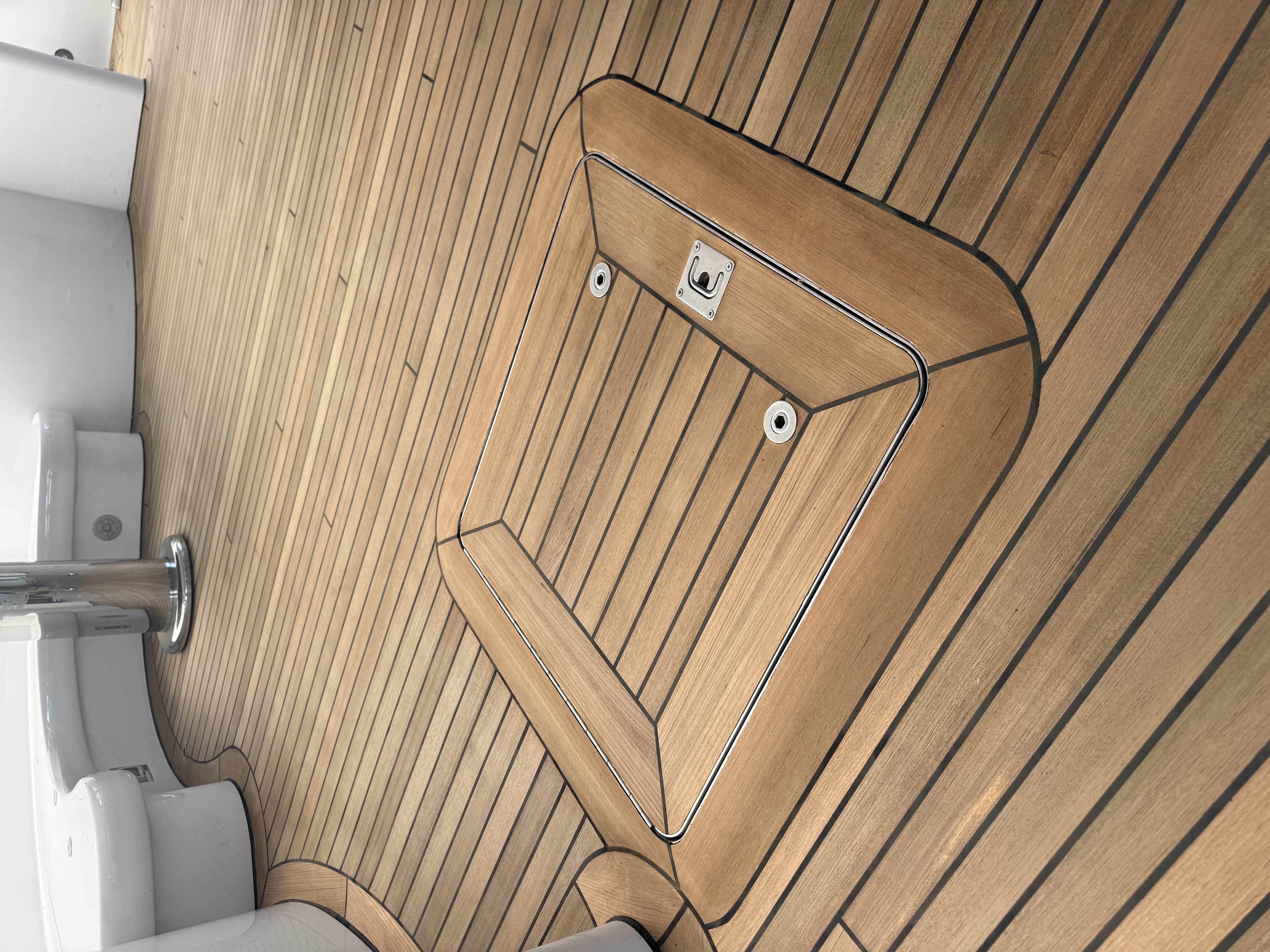 Finished yacht teak deck with a flush hatch framed by mitered teak border planks