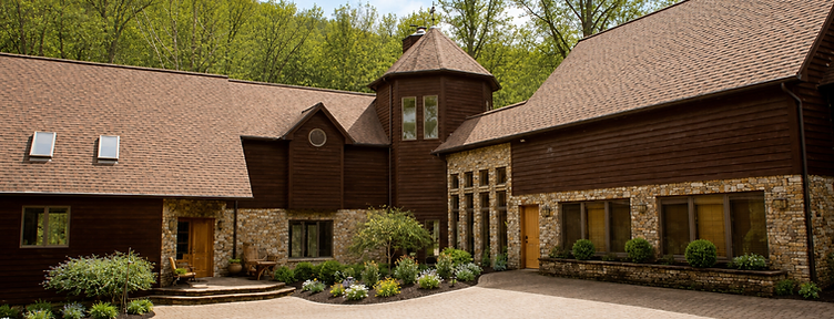 The Camp Baer campus exterior, warm wood and stone nestled in the West Virginia forest