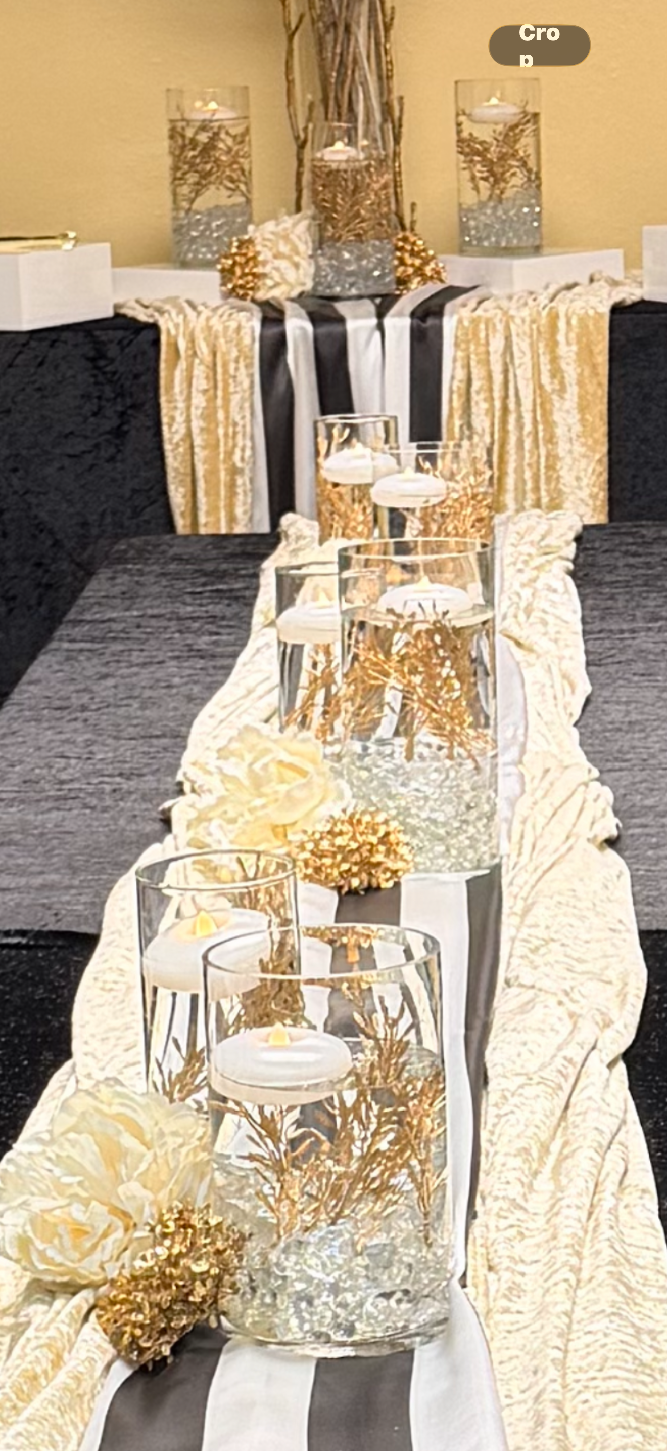 Gold and black tablescape with floating candle vases, submerged gold branches and cream peonies on a striped runner