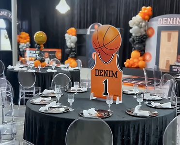 Basketball-themed kids party with orange and black balloons, custom jersey centerpiece, and elegant table setting