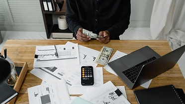 Bills, financial statements and a calculator laid out on a desk while debt payments are planned.
