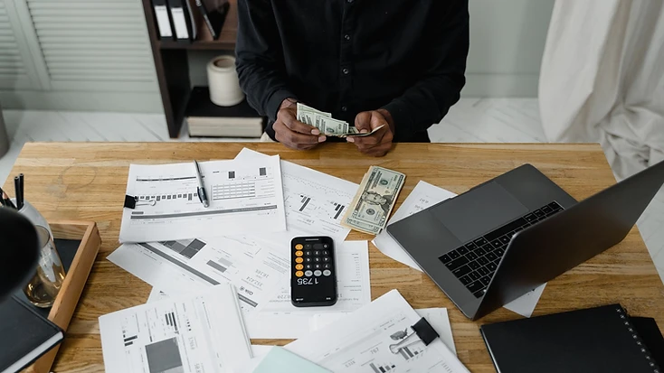Bills, financial statements and a calculator laid out on a desk while debt payments are planned.