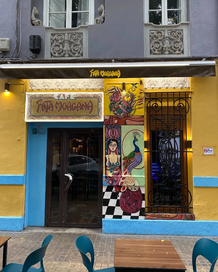 Fachada de Fata Morgana Café con el mural y el cartel de neón