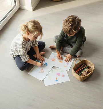 Zwei Kinder malen auf hellem, versiegeltem Boden