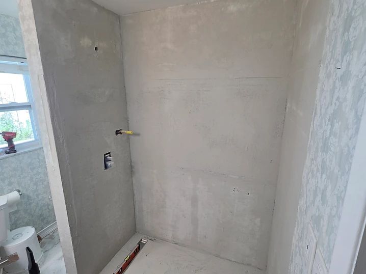 Cement board shower walls with plumbing cutouts prepared before waterproofing
