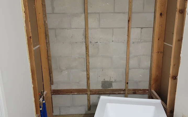 Exposed wall framing and a set-in bathtub during the early construction phase of a bathroom remodel in Largo, FL