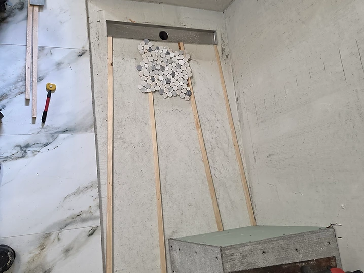 Close-up of shower pan slope battens and stainless steel linear drain channel