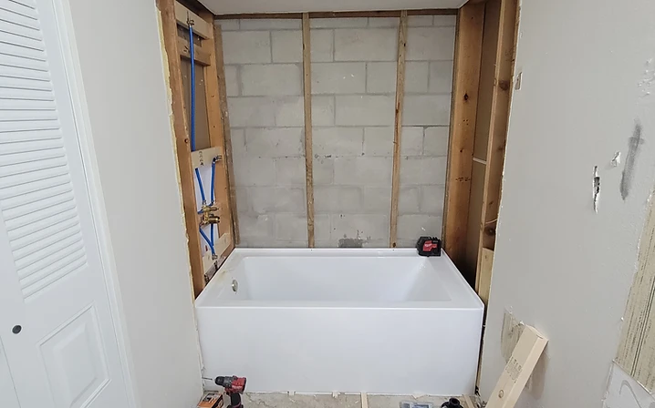 New white bathtub installed against the bare cinder block wall during a Largo, FL bathroom remodel