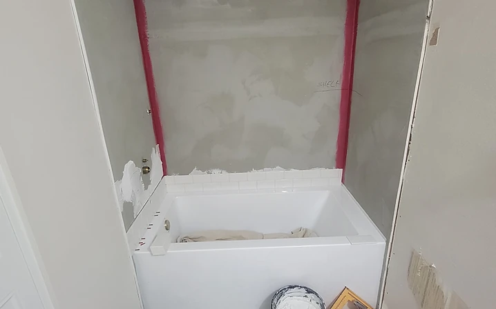 Cement board and waterproofing membrane on the shower wall above the new black-and-white patterned floor tile