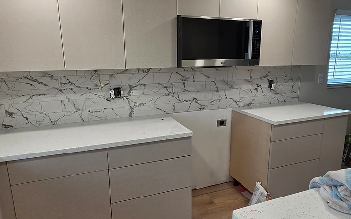 Modern marble-look backsplash with light kitchen cabinets installed by Dream Tiles, Inc.