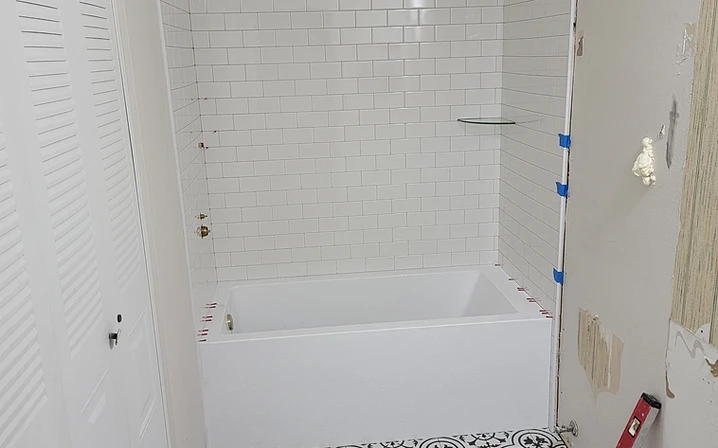 White subway tile installed on a tub surround in a running bond pattern with spacers and a spirit level