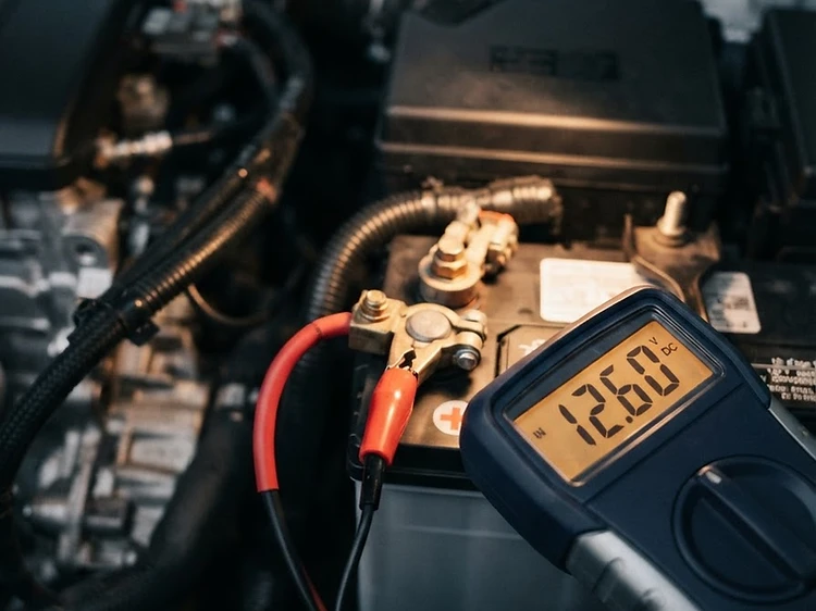 Digital multimeter showing 12.6 volts reading on a vehicle battery terminal