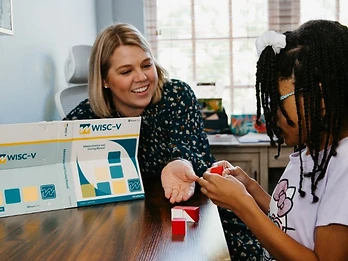 A clinician and child working together at a table with testing materials