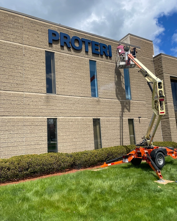 On-site installation: a crew in a boom lift mounting large channel letters onto a commercial building facade
