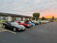 Vintage and modern cars lined up under the portico at sunset