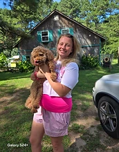 Chloe holding a goldendoodle puppy outside the barn