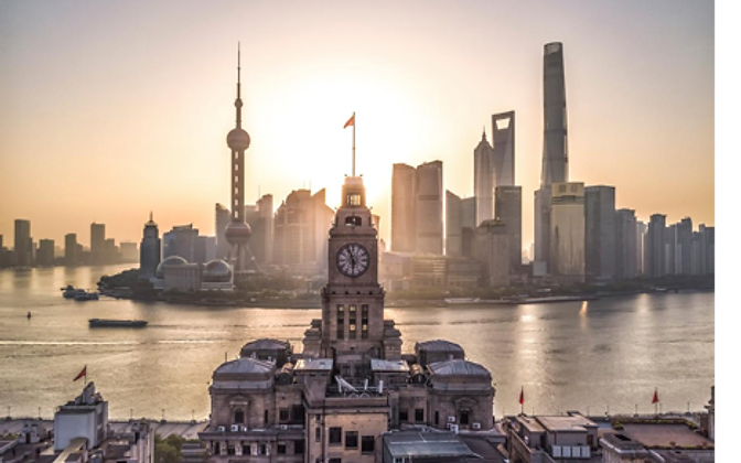 Sunrise over The Bund — the Customs House clock tower in the foreground, Pudong's skyline across the Huangpu River