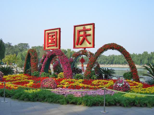 National Day floral decorations — red-and-gold displays and "国庆" (Guóqìng) signage in a public park