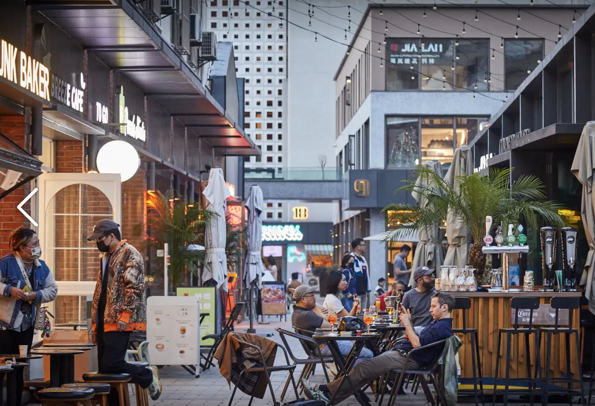 The pedestrian lane through Shankang Li — string lights, outdoor bar counters, and Drunk Baker glowing on the left.