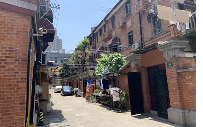 A lilong lane — red-brick shikumen houses, laundry lines and a stone gate entrance