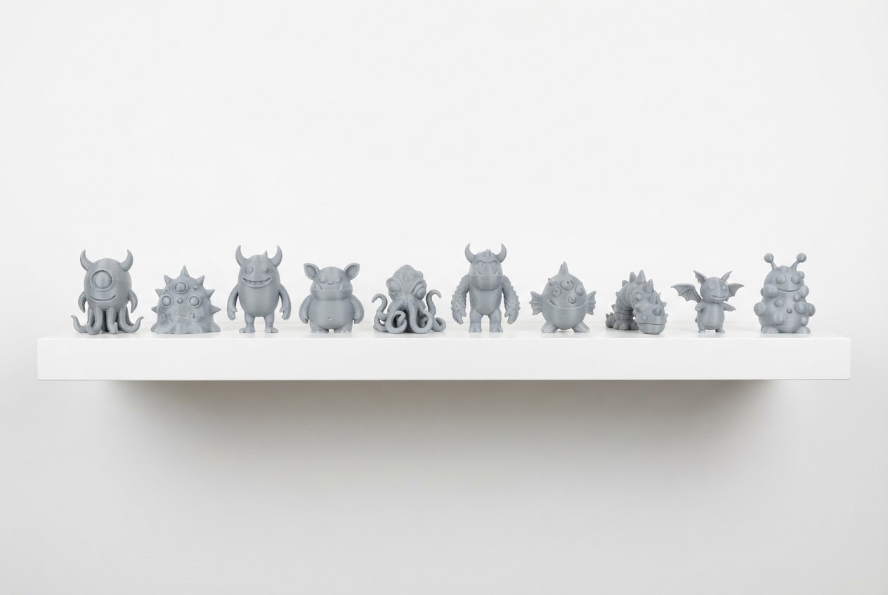 A shelf of unique custom 3D printed grey PLA monster toys made from kids drawings