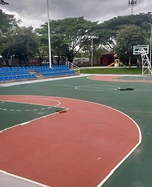 Cancha de baloncesto y fútbol con pintura roja y verde, graderías azules y torre de iluminación