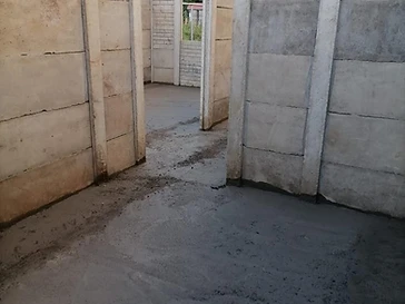 Interior con muros de paneles prefabricados de concreto y piso de concreto recién vaciado durante la obra.
