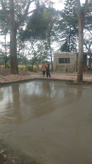Superficie de concreto fresco recién nivelado con trabajadores supervisando el proceso