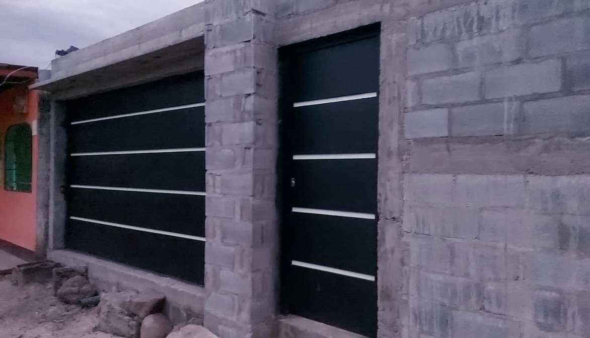 Puerta de garaje y puerta lateral instaladas en muros de bloque sin repellar