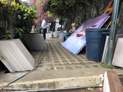 Trabajador en pasadizo de adoquines con materiales de remodelación apilados