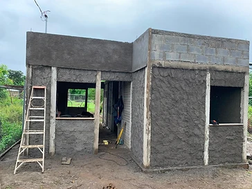 Vivienda de un nivel en construcción con acabado de estuco crudo y columnas de concreto expuestas.