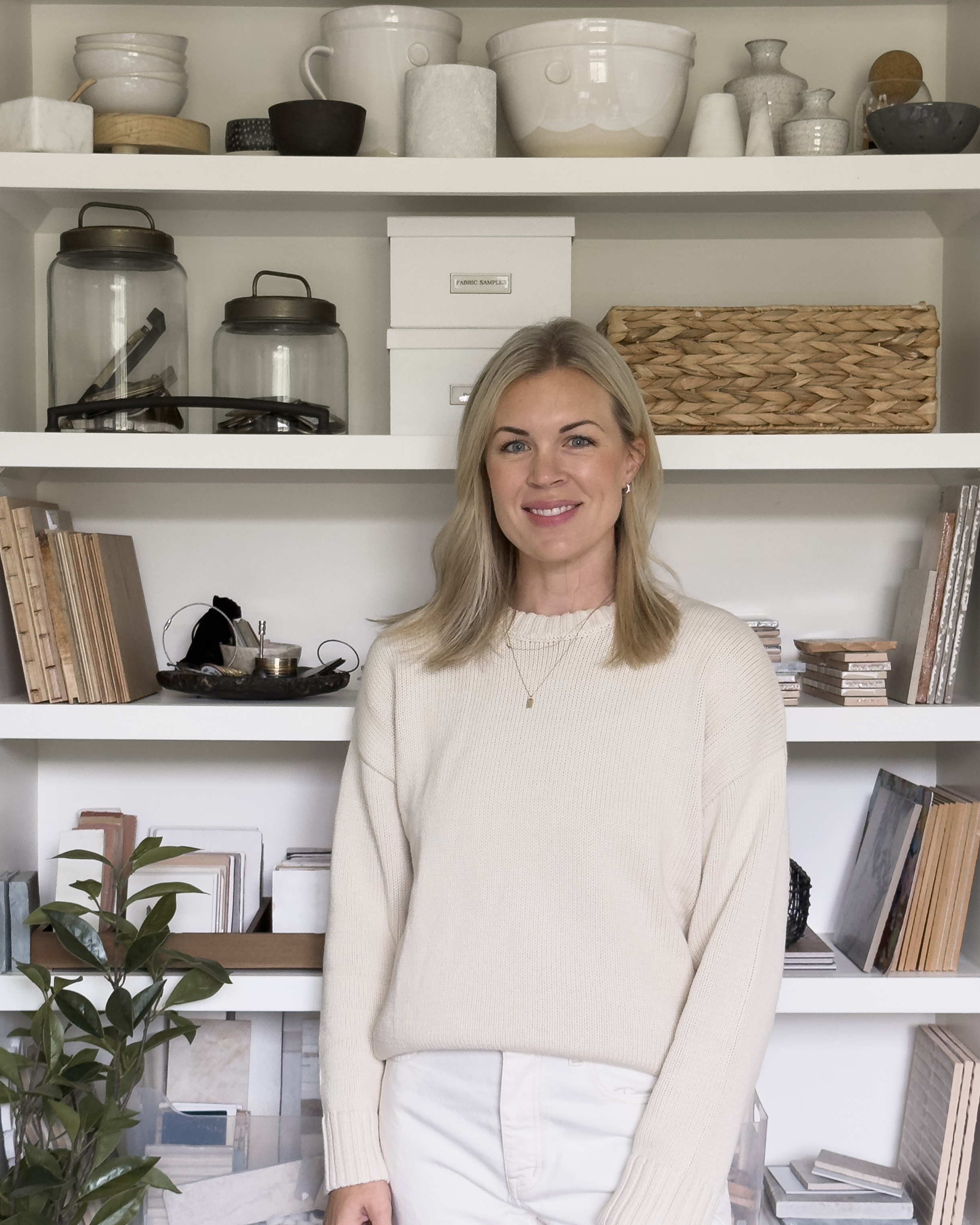Interior designer reviewing fabric swatches and a floor plan at a wooden desk in warm window light