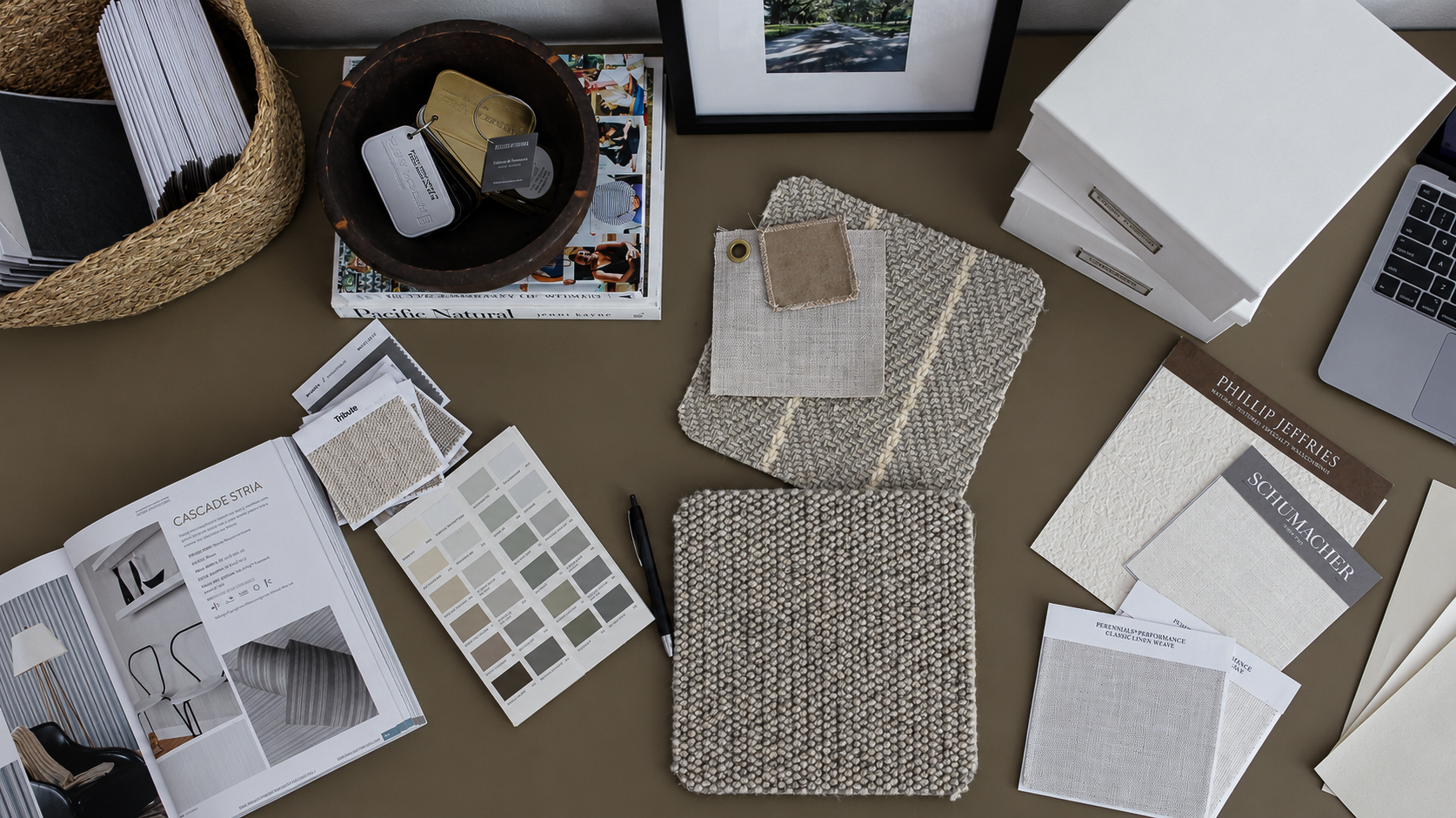 Designer's workspace flat lay with fabric samples, paint swatches, wallcovering cards, and hardware