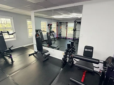 Adjustable weight benches, dumbbell rack, and mirror wall in the training studio