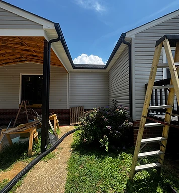 Integrity Gutters job in progress — new black seamless gutters and downspouts going up on a home with the ladder still set