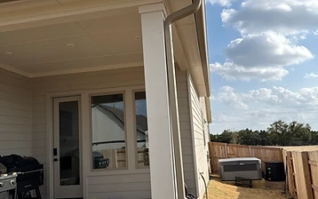 New color-matched downspout on a covered patio column carrying roof runoff away from the slab